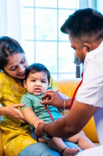 Indian doctor checks infant baby boy with stethoscope while mother holds him in arms during regular health examination in modern clinic, ensuring child wellness, love, care, early health monitoring