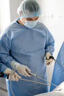 Two surgeons in uniform stand with endscopes preparing for minamal invasive procedure for a patient in operating room. Concept of endoscopic-computer assisted treatment